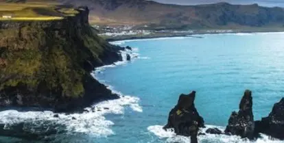 black rocks surrounded by water with mountains