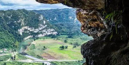 view through rocks to green grass and mountains