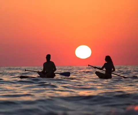 Man and woman on paddleboard at sunset