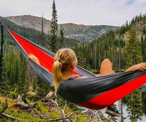 Woman relaxing on red hammock watching the mountains