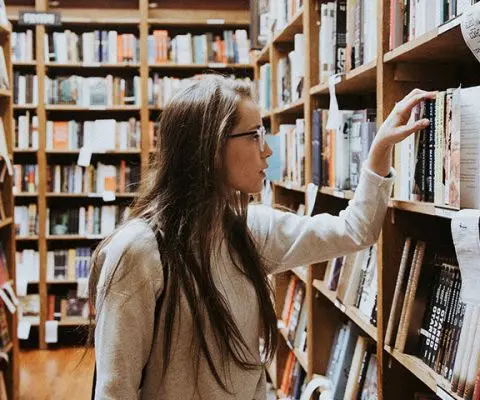 Girl in library reaching for book
