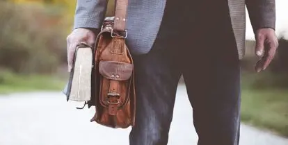 man carrying a bag and a book
