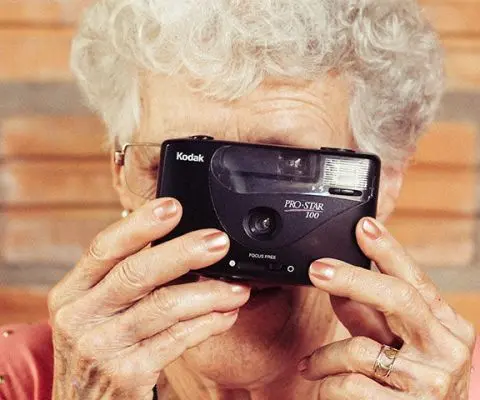 old woman taking a picture using an old camera