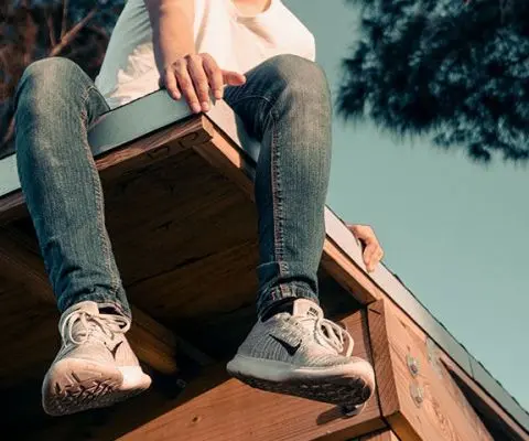 teenager's legs dangling while sitting on the roof