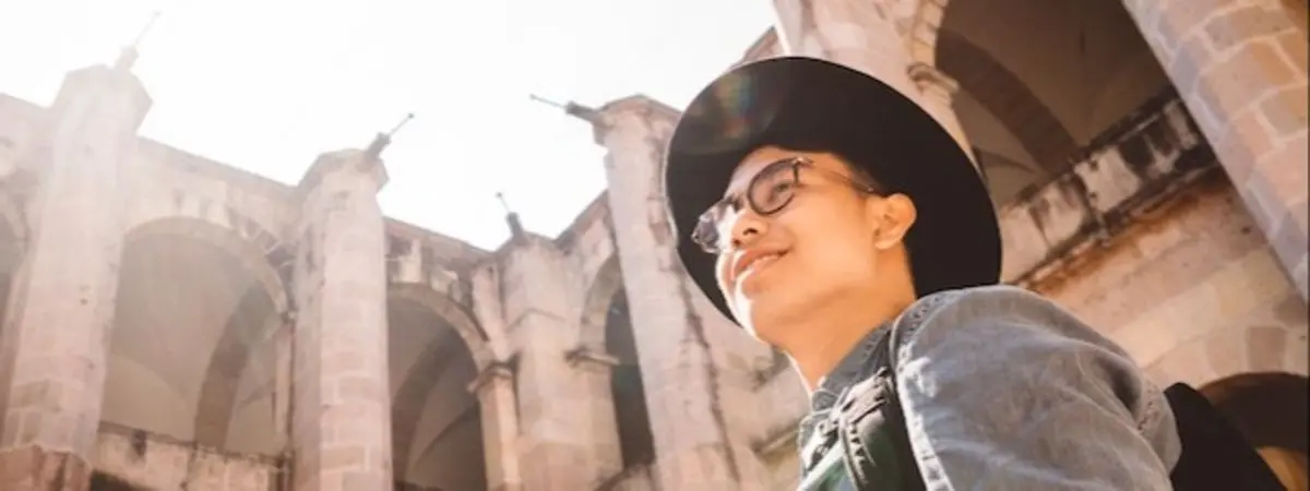 person wearing hat smiling and looking up at building