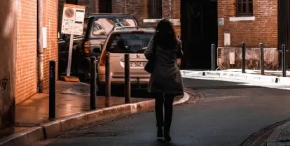 person walking on street surrounded by brown buildings