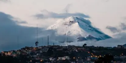 view of cotopaxi volcano from quito at sunrise with buildings at the bottom