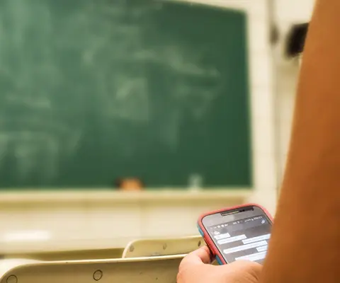 man writing on blackboard, student on phone