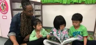 ITA teacher sitting on the floor with her students