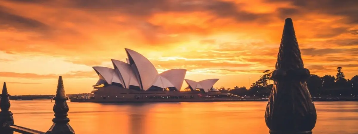 distant view of opera house next to water under orange sky