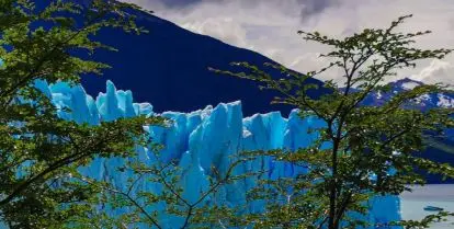 mountain behind blue ice glacier and green treesv